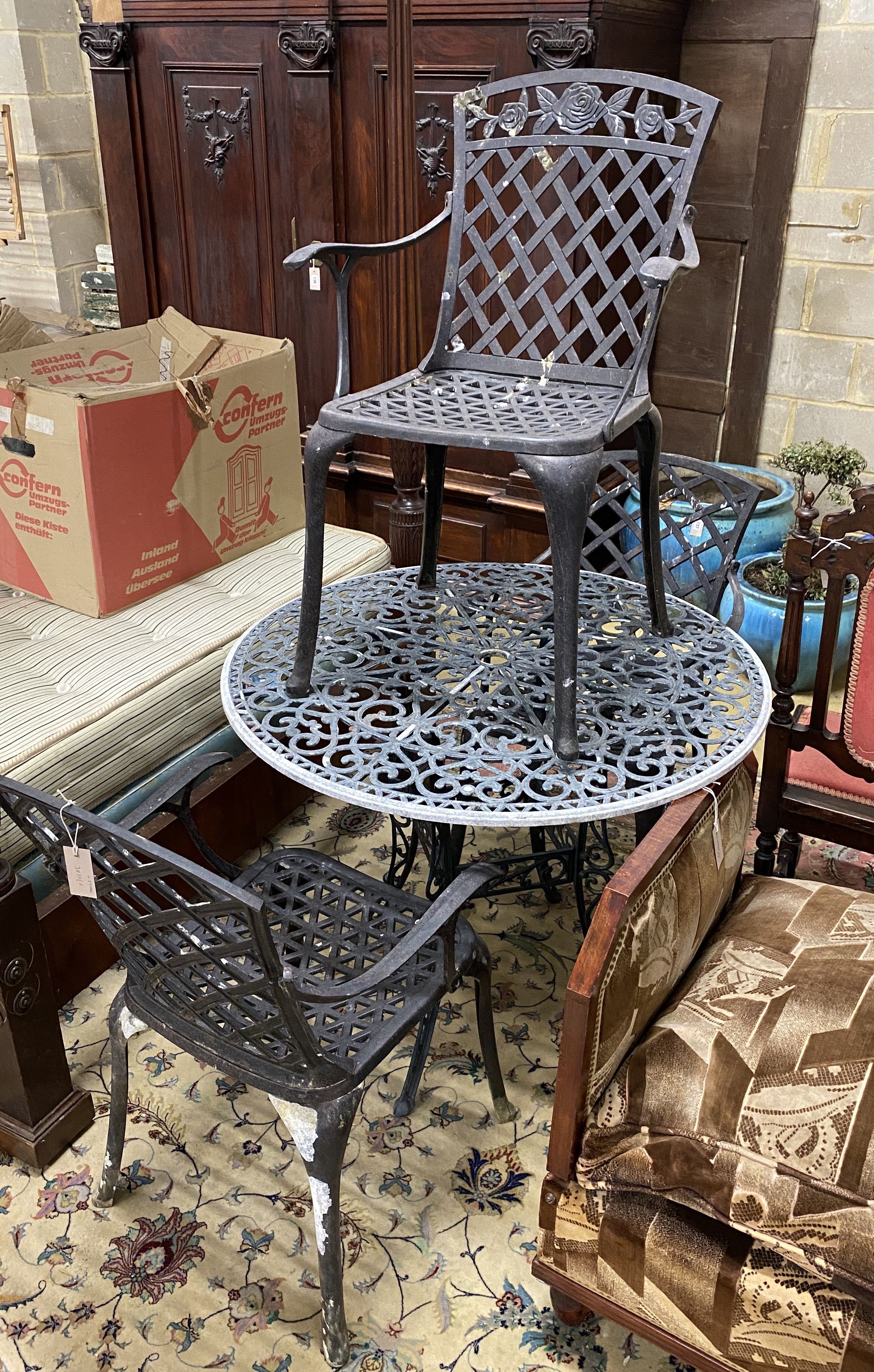 A circular painted aluminium garden table and three elbow chairs